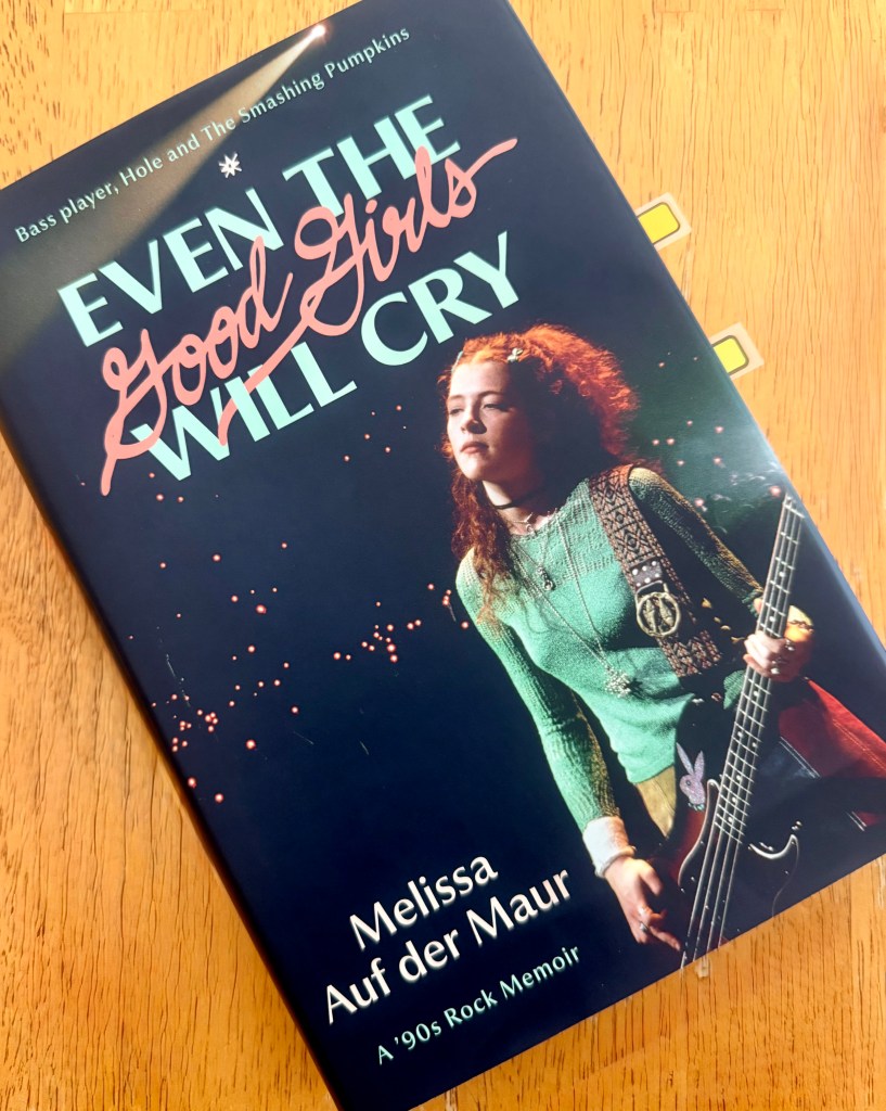 Hardcover book of Even The Good Girls Will Cry: A ‘90s Rock Memoir by Melissa Auf der Maur. I photo of Auf der Maur playing Bass.
